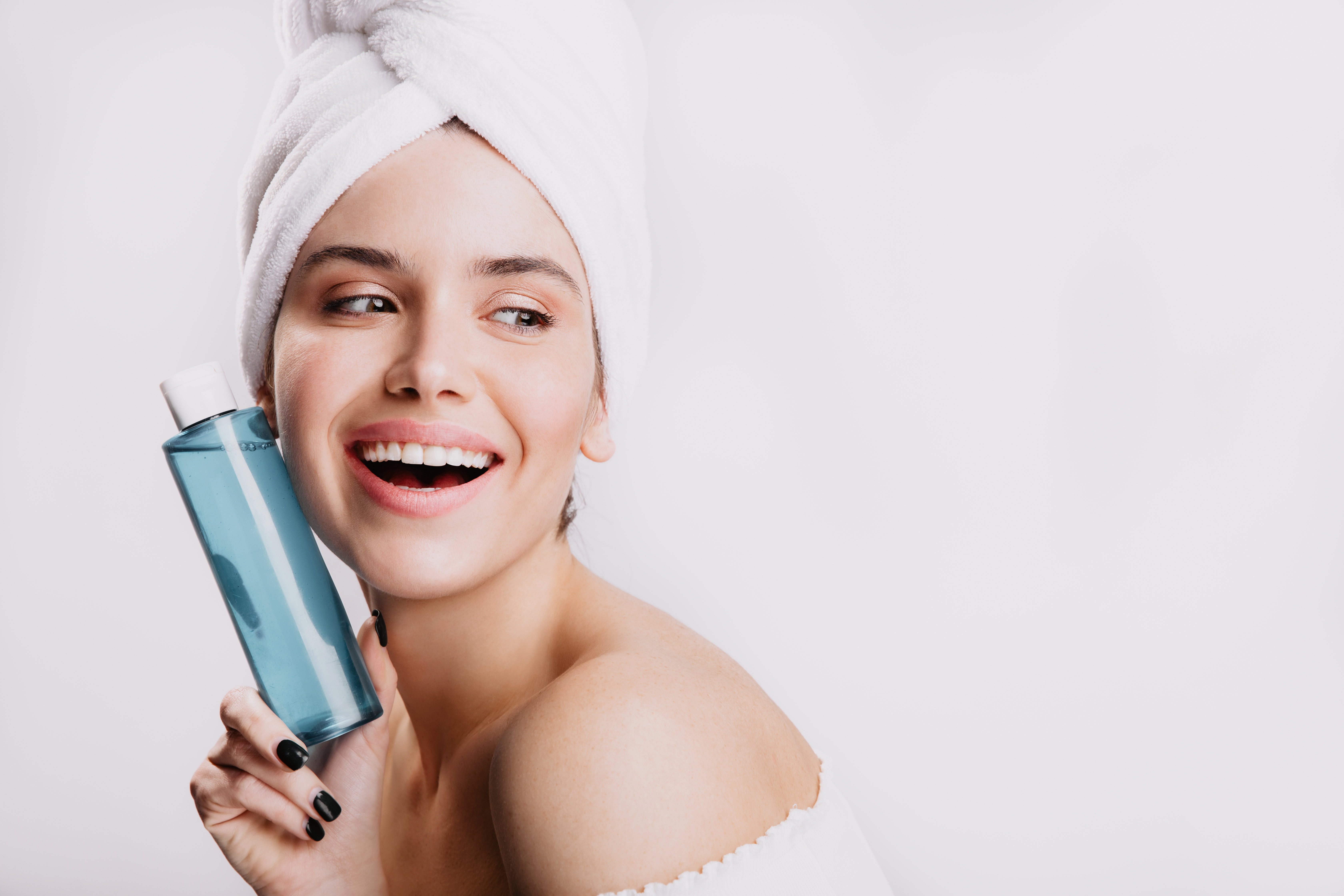 satisfied-female-model-without-makeup-smiling-white-wall-girl-after-shower-posing-with-bottle-cosmetic-tonic